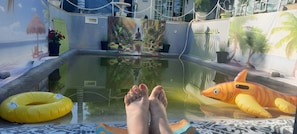 A pool area with a mural, inflatable toys, and a Buddha statue.