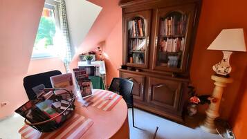 Een gezellige kamer met een ronde tafel, boekenkasten, een lamp en een raam.