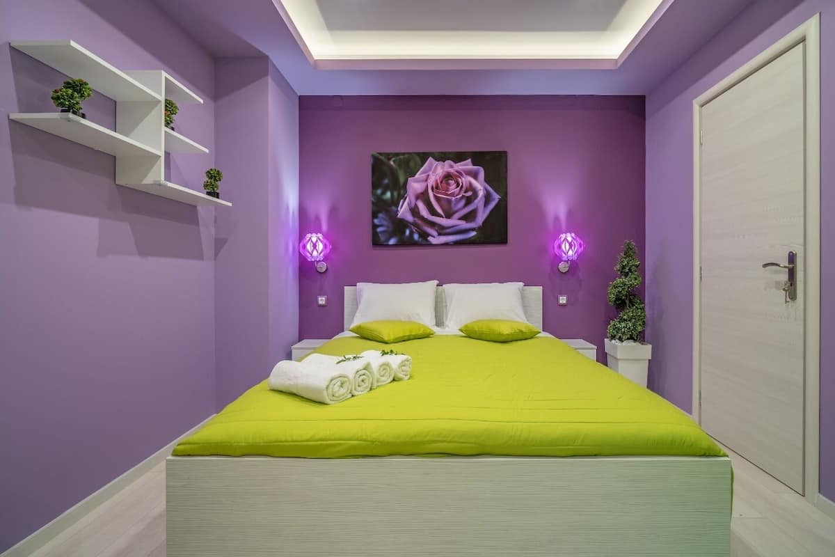 Une chambre à coucher comprenant un lit, une étagère fixée au mur, une porte et un luminaire fixé au mur.