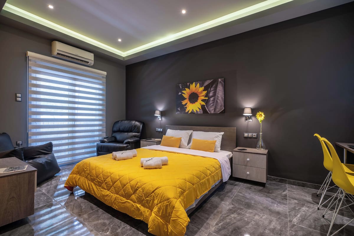 Une chambre moderne avec un grand lit, un bureau, une chaise et un coin repas.
