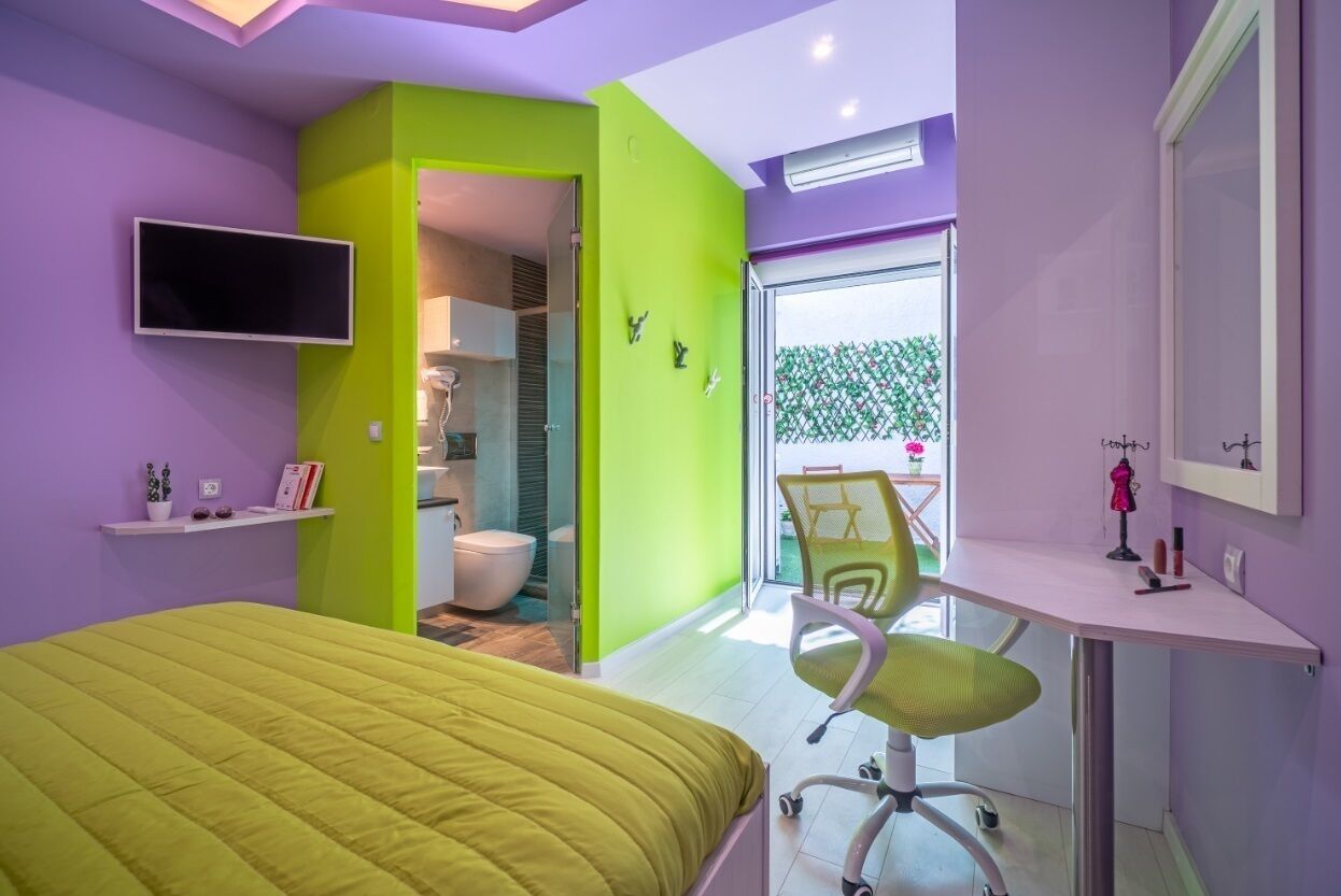 A modern bedroom with a green accent wall, a bed, a desk, and a chair.