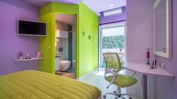 A modern bedroom with a green accent wall, a bed, a desk, and a chair.