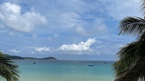 Une plage à l’eau turquoise et limpide, avec un rivage sablonneux et une terrasse en bois.