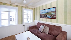 Ein Zimmer mit einem braunen Sofa, einem weißen Couchtisch und einem Landschaftsbild an der Wand.