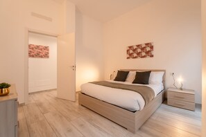 Une chambre à coucher moderne avec un lit en bois, des tables de chevet et des œuvres d’art accrochées aux murs.