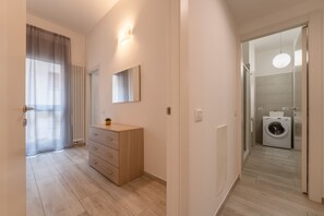 Une salle de bain moderne équipée d’un lave-linge intégré, d’un miroir et d’un luminaire mural.