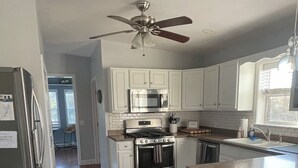 Una cocina moderna con armarios blancos, electrodomésticos de acero inoxidable y piso de madera.
