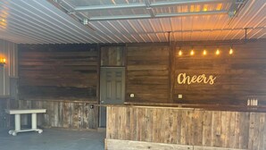 Un área de recepción con pared de madera, un letrero de neón que dice 'Cheers' y piso de baldosas.