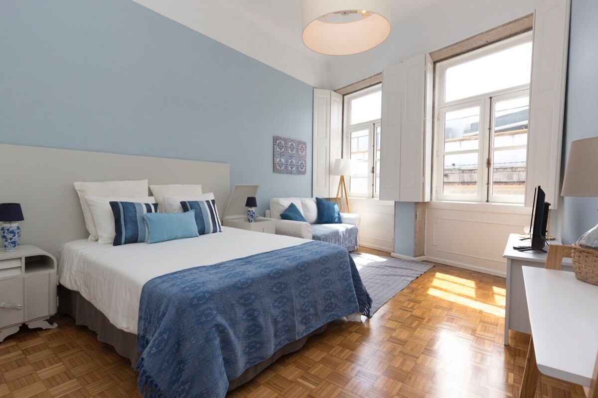 Ein Schlafzimmer mit einem großen Bett, zwei Nachttischen, einem Schreibtisch und einem Fenster.