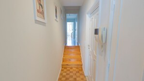 Un couloir doté d’un plancher en bois, de murs blancs et de tableaux encadrés.