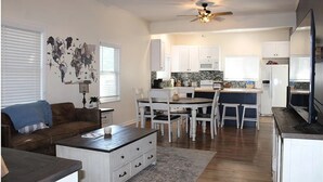 A spacious living area with a dark wooden coffee table, white cabinets, and a world map mural.