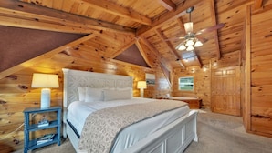 A cozy wooden cabin bedroom with a bed, nightstands, and a ceiling fan. - Bearly Behavin’ | Hot Tub, Pool, Arcade Game, MORE (Pigeon Forge)