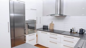 Eine moderne Küche mit Edelstahlgeräten, weißen Schränken und einer schwarzen Arbeitsplatte.
