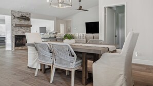 Een moderne woonkamer met een eethoek, met een open haard, een plafondventilator en een grote televisie.