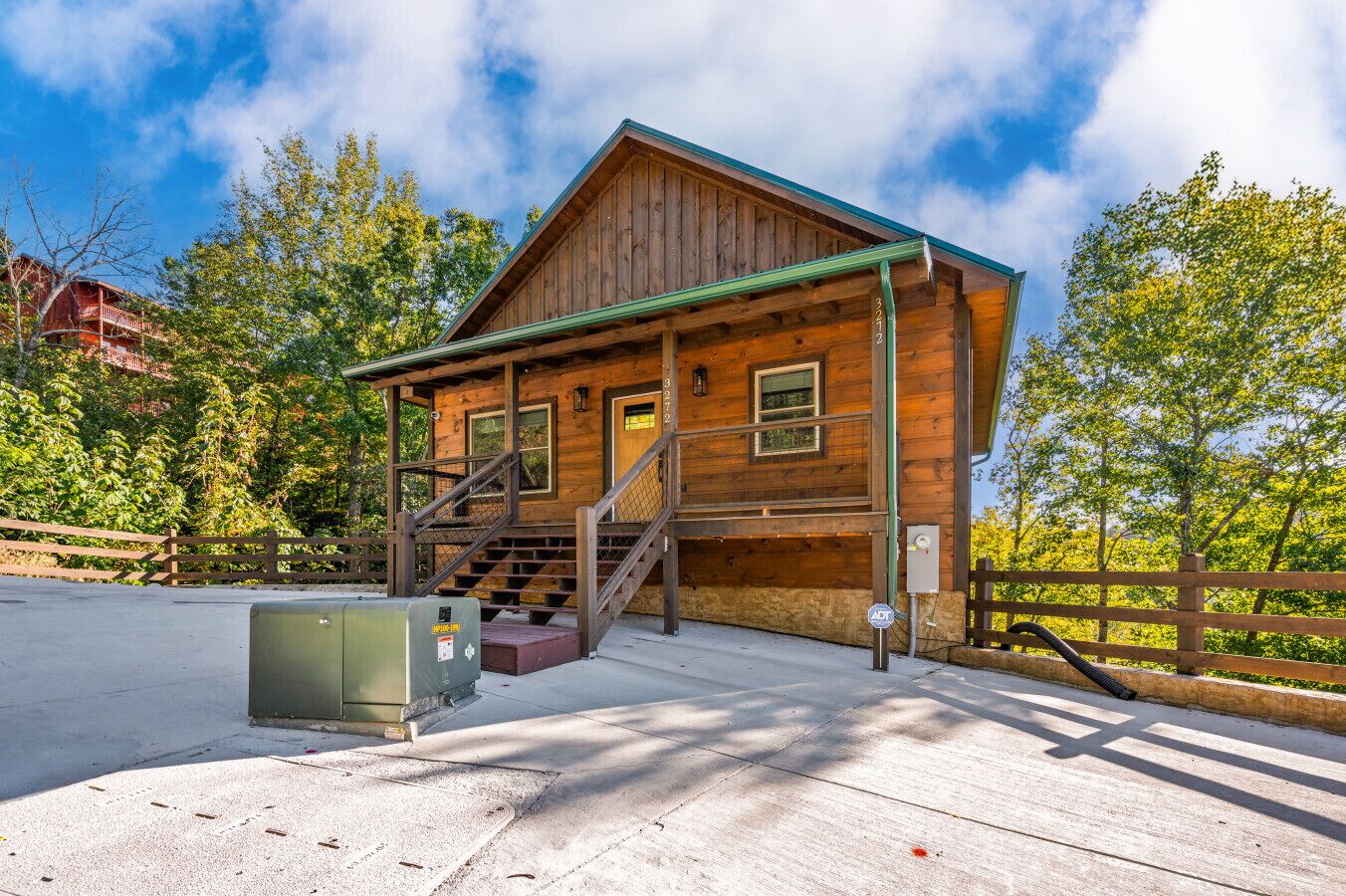 A wooden cabin with a porch and stairs, surrounded by trees.