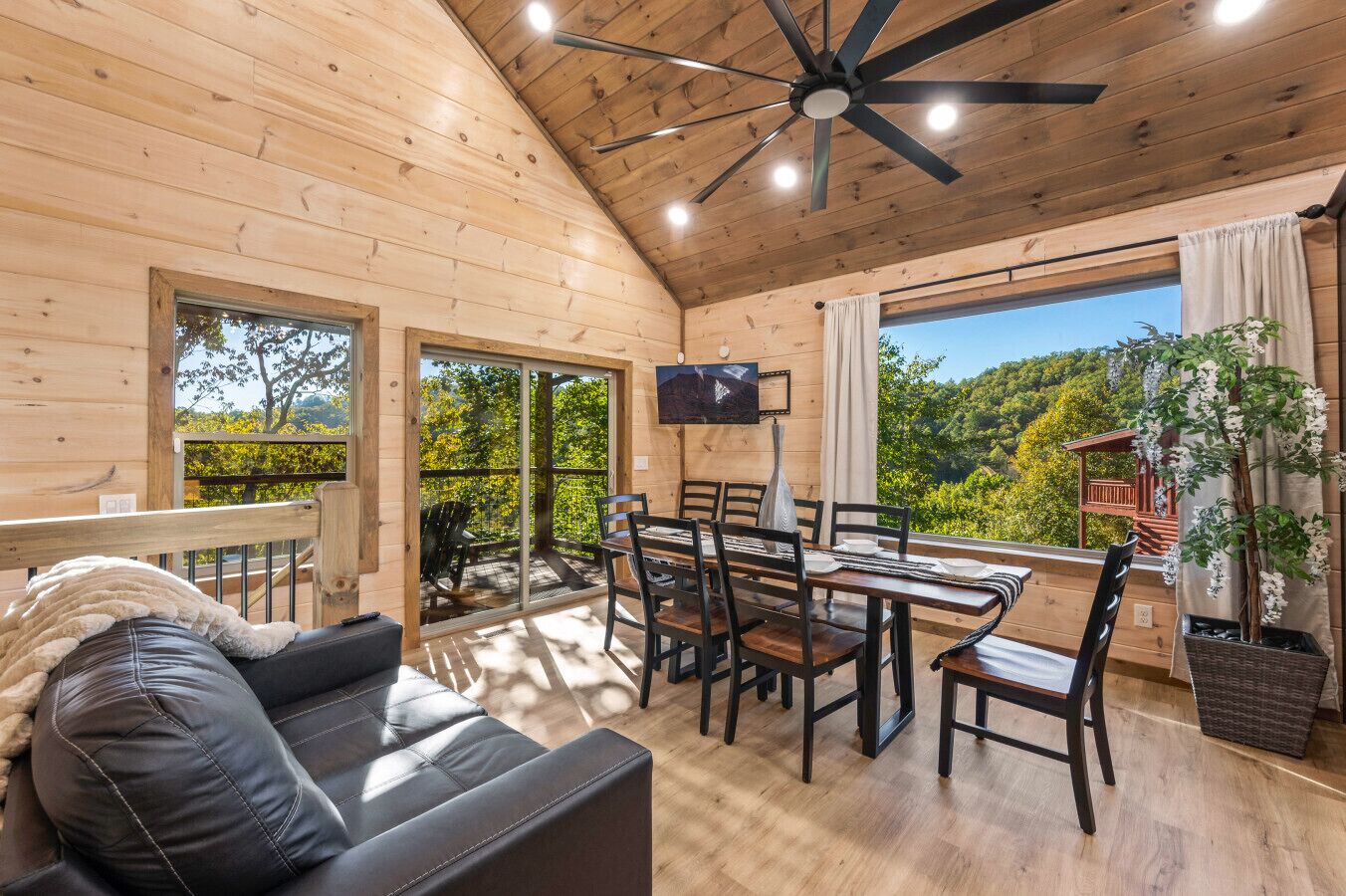 Une cabane en bois comprenant un coin repas, un canapé et un téléviseur.