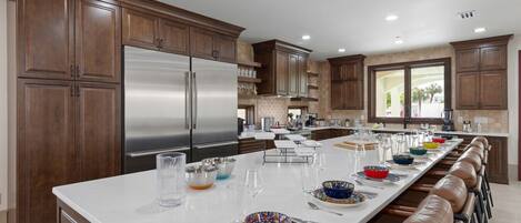 A spacious kitchen with a long island, stainless steel appliances, and wooden cabinets.