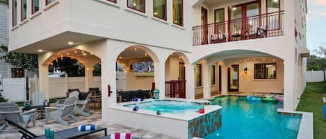 A two-story house with an outdoor swimming pool, lounge chairs, and a covered patio area.