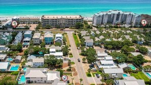 Vue aérienne d’une zone résidentielle côtière, avec des maisons, une plage et un hôtel.