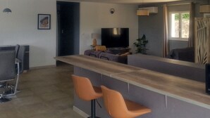 Une cuisine moderne avec un coin bar, une table à manger et un téléviseur.