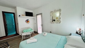 A bedroom with a bed, a chair, a mirror, and a television.