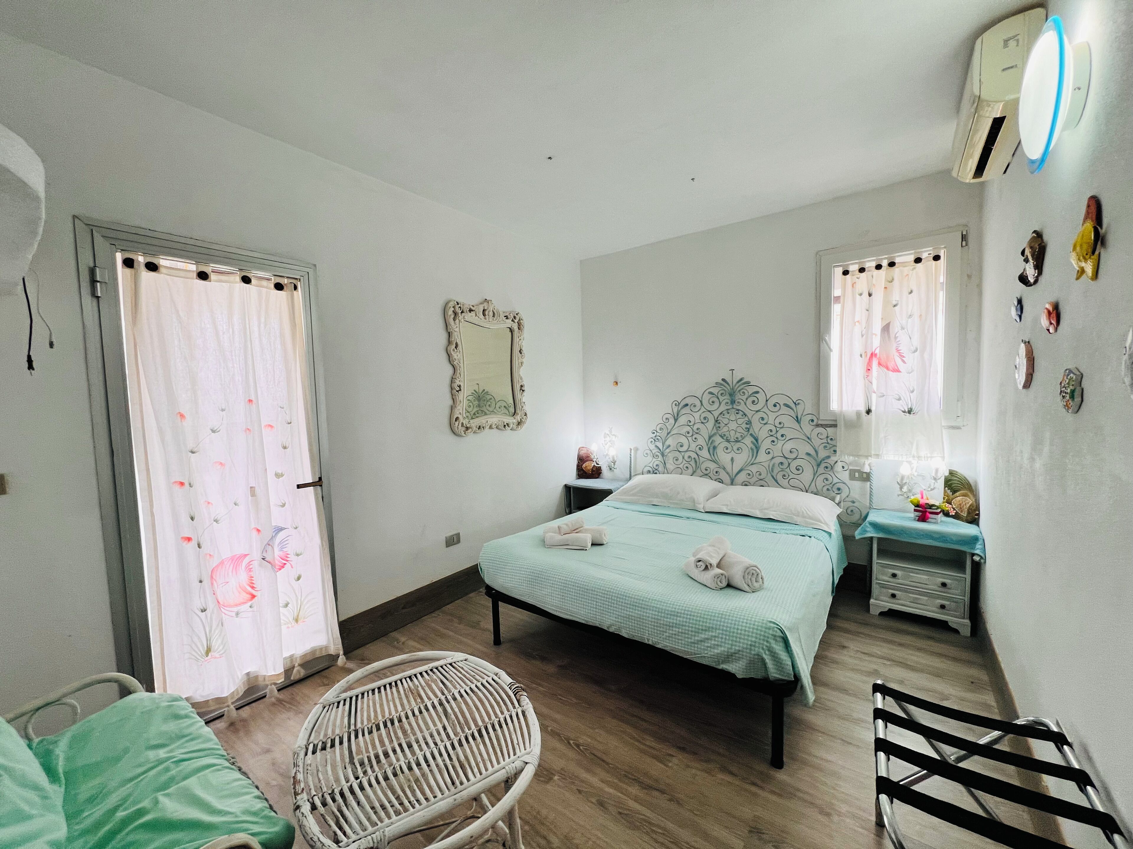 Ein Schlafzimmer mit einem Bett, einem Sessel, einem Nachttisch und einer Wand-Klimaanlage.