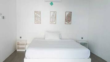 A hotel room with a large bed, two bedside tables, and three wall-mounted artwork pieces.