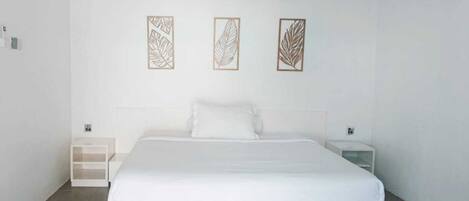 A hotel room with a large bed, two bedside tables, and three wall-mounted artwork pieces.