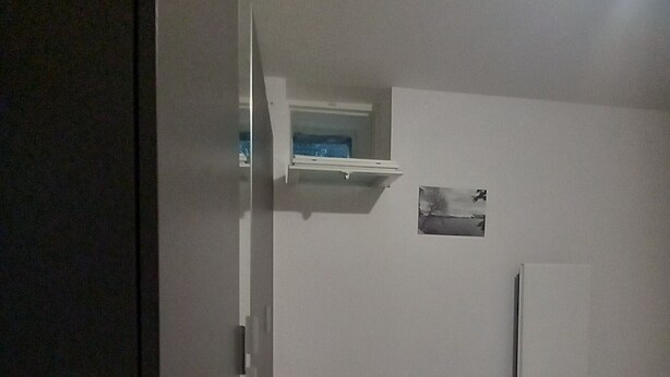 Un dormitorio con una cama, un estante pequeño y un cuadro colgado en la pared.