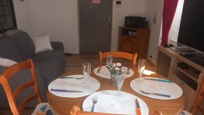 Un comedor con una mesa redonda dispuesta para cuatro personas, rodeada de sillas de madera con asientos acolchados.