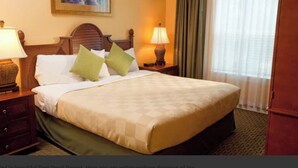 A hotel room with a large bed, two bedside lamps, a wooden headboard, and a view of a window with curtains. - Most Relaxing Resort Hilton Head Island, SC-Close to Beach-3 Bedroom, 3 Bathroom (Hilton Head Island)