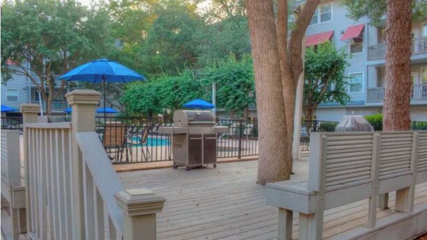 A wooden deck with a grill, two blue umbrellas, and a pool in the background. - Most Relaxing Resort Hilton Head Island, SC-Close to Beach-3 Bedroom, 3 Bathroom (Hilton Head Island)