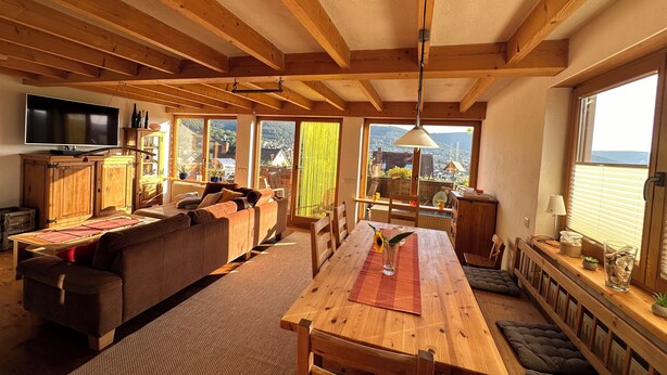 A cozy wooden interior with a dining area, sofa, and TV. - FEWOBuergstadt.de Light-flooded, cozy, spaciousFeWo with distant view (Bürgstadt)