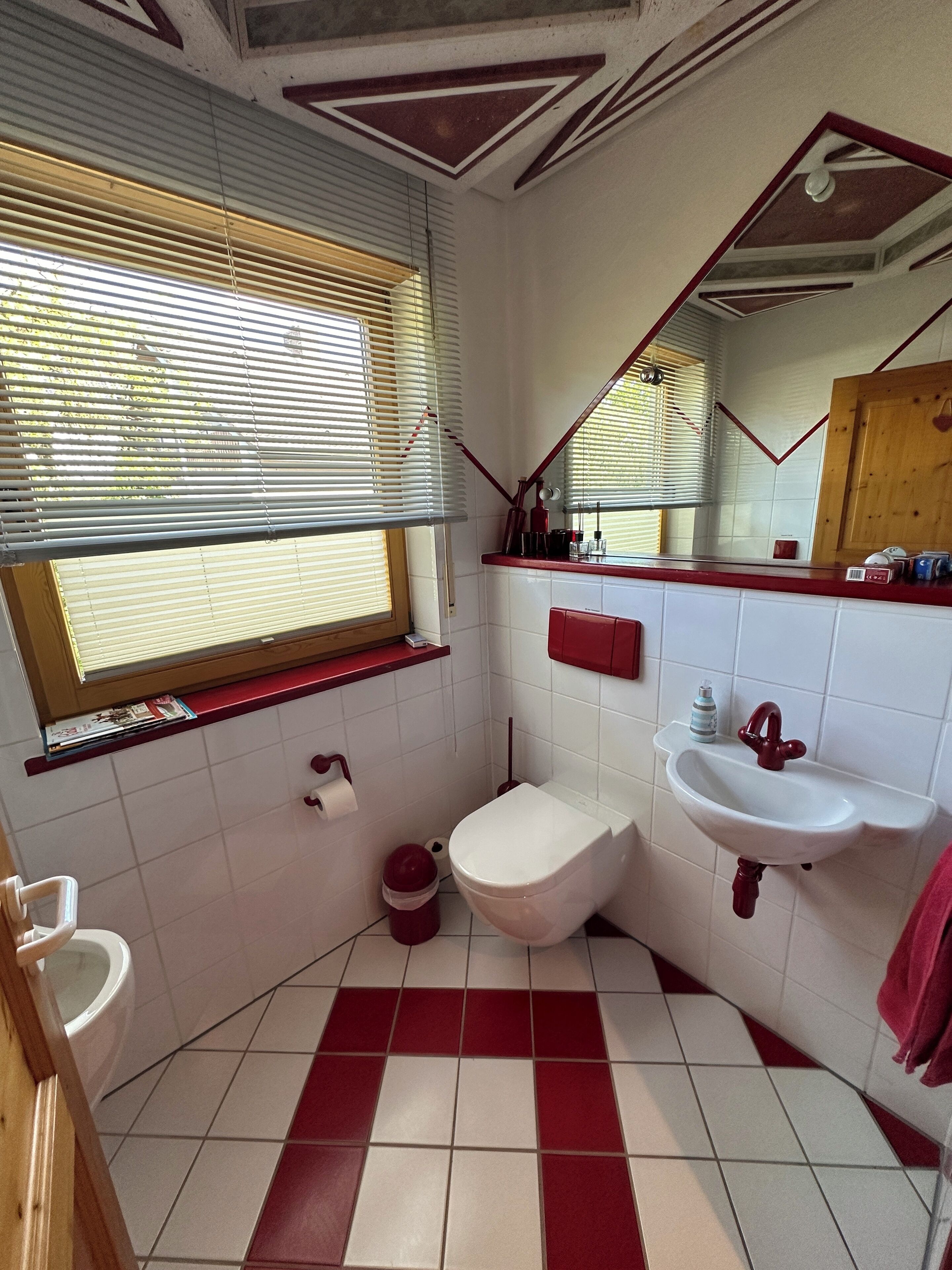 A bathroom with a toilet, sink, and window.