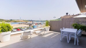 Ein Balkon mit Blick auf den Strand, einem Tisch, Stühlen und Topfpflanzen.