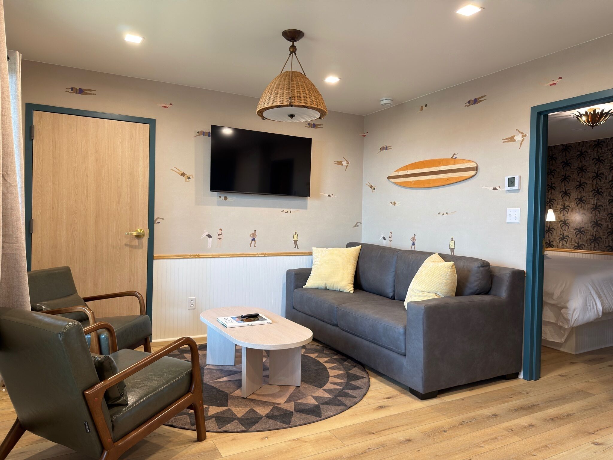 A modern room with a grey sofa, a wooden door, a television, and a patterned wall.