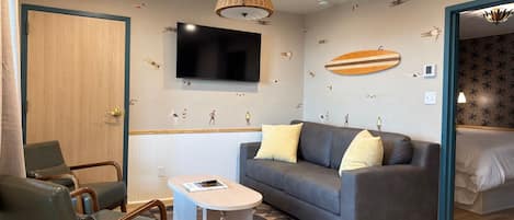 A modern room with a grey sofa, a wooden door, a television, and a patterned wall.