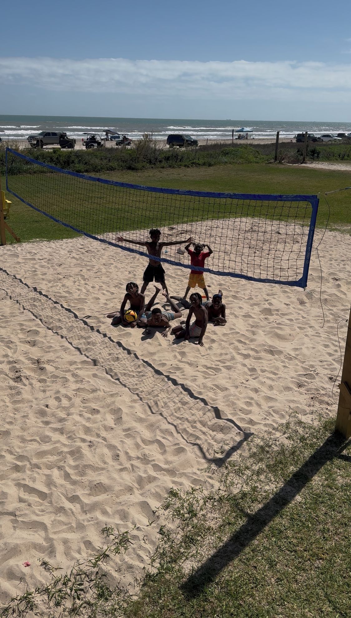 Una cancha de voleibol de playa con jugadores y una red.