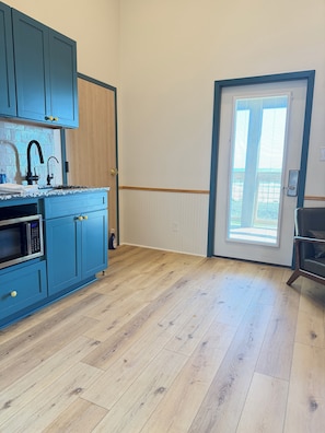 A kitchen with blue cabinets, a microwave, and a sink. - The Breeze Beachfront Resort (Surfside Beach)