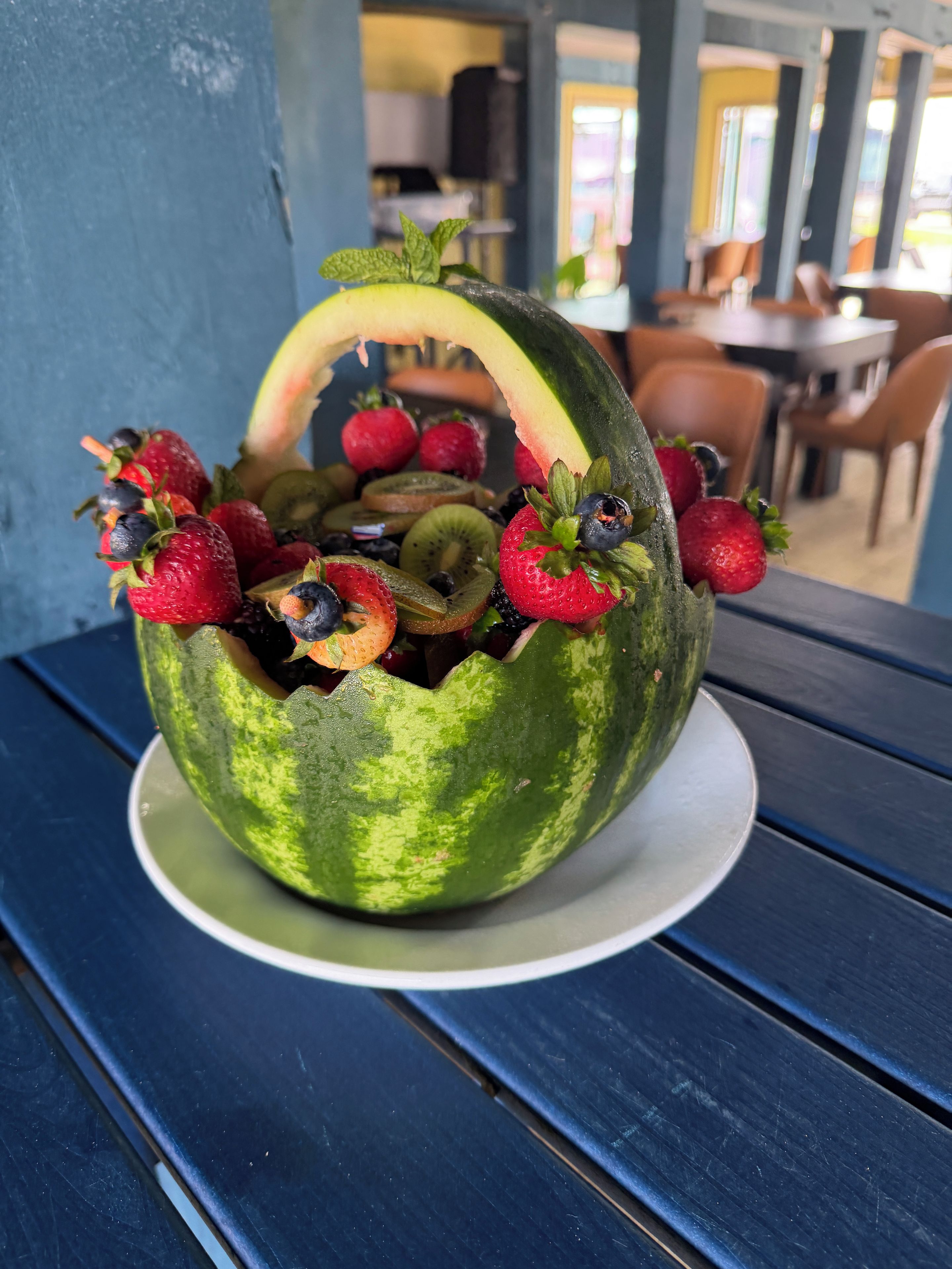 A fruit arrangement in a watermelon bowl on a table.