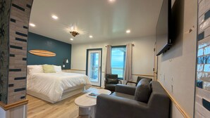 A modern hotel room with a large bed, a sofa, a coffee table, and a TV mounted on the wall. - The Breeze Beachfront Resort (Surfside Beach)