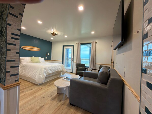 A modern hotel room with a large bed, a sofa, a coffee table, and a TV mounted on the wall. - The Breeze Beachfront Resort (Surfside Beach)