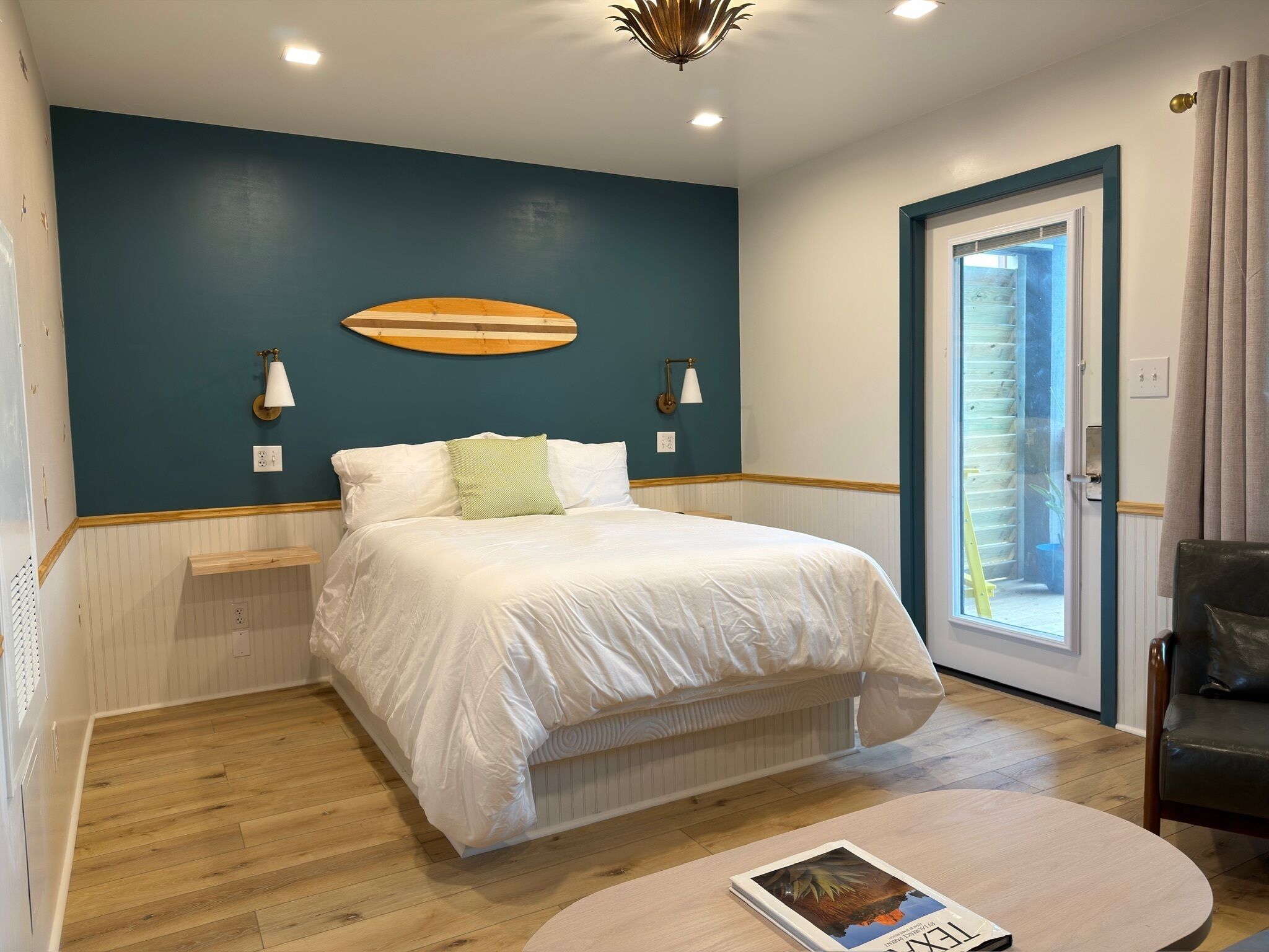 Quarto com uma cama, mesa de cabeceira, luminária e vista para o exterior.