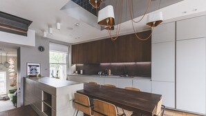 Una cocina moderna con una isla central, sillas de madera e iluminación colgante.