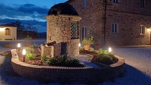 Een gebouw van steen met een koepel en een ronde stenen constructie met planten en verlichting.