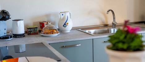 Een keuken met een spoelbak, waterkoker, broodrooster en koffiezetapparaat op het aanrecht.