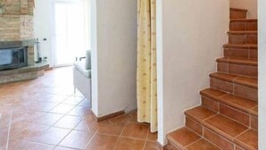 Un interior espacioso con suelo de baldosas, una escalera y una chimenea.