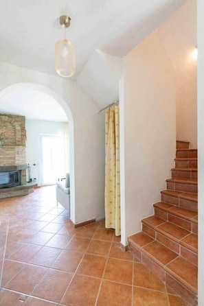 A spacious interior with a tiled floor, a staircase, and a fireplace. - Poderino il Sole - Casa Quercia (Lajatico)