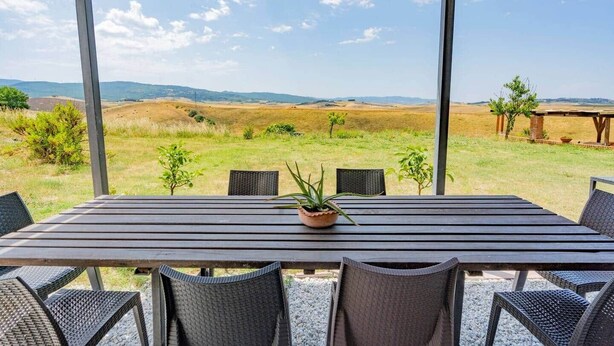 Un espacio de comedor al aire libre con techo, con una mesa y sillas, con vistas a un paisaje pintoresco.
