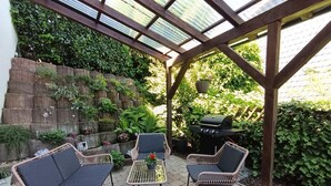 An outdoor patio with wicker furniture, a grill, and a glass-enclosed structure. - NEW! Time out at the Hirzenkopf (Steinberg-Deckenhardt)